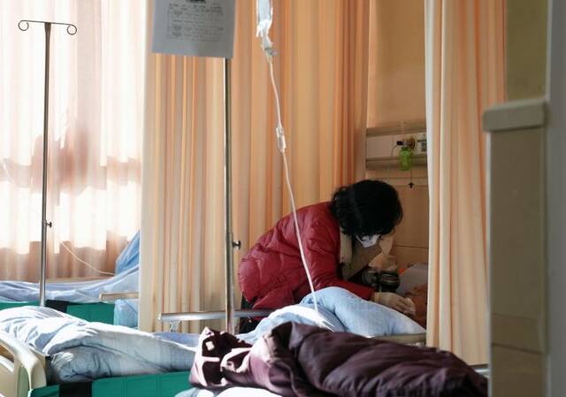 1月4日，在九亭镇社区卫生服务中心的病房，居民唐女士在照顾90岁的母亲。（新华社记者刘颖摄）