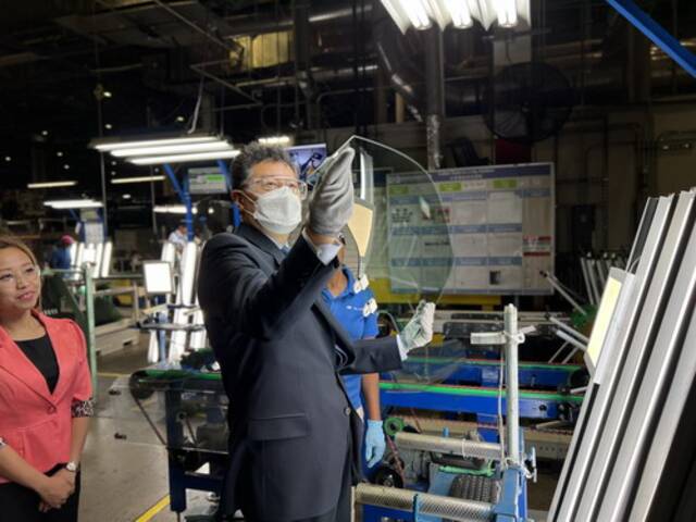 2022年9月7日，在福耀汽车玻璃生产基地，工人们邀请秦刚参观玻璃的配件安装工序。外交部网站图