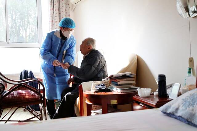 1月7日，在上海中福会养老院，驻院医生彭俊（左）给老人做血氧监测。