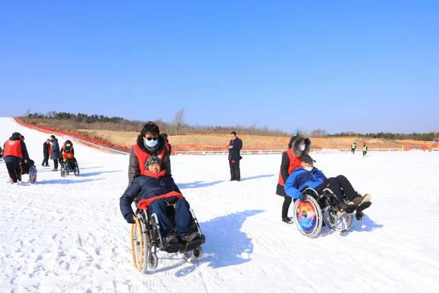 图为残障人士在长城爱心大本营志愿者的帮助下体验滑雪。（受访者供图）