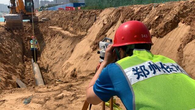 渠南路给水管道新建工程工地，地表温度50℃，三强公司职工正在铺设供水管道