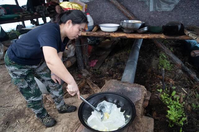 在漠河林场森林抚育队伍的临时帐篷内，闫秀艳用冰块炖菜。新华社记者张涛摄