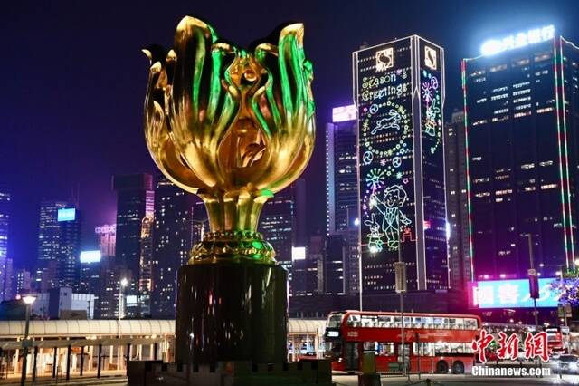 1月19日，香港金紫荆广场的“永远盛开的紫荆花”铜雕与周边大厦的贺年灯饰交相辉映。农历新年即将到来，香港街头的新春气氛越来越浓。中新社记者李志华摄