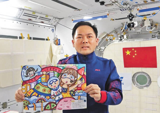 穿着“祥云服”的航天员张陆在展示“天宫画展”青少年绘画作品。中国载人航天工程新闻宣传办公室供图