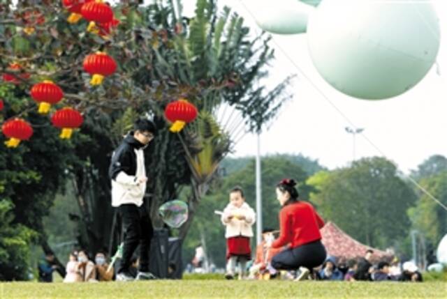 ▶春节假期家长带孩子在万绿园草坪玩耍。本报记者苏弼坤摄