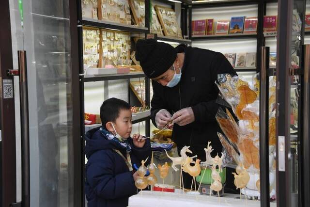 1月22日，在北京烟袋斜街的一家店铺，小朋友体验吹糖人。新华社记者任超摄