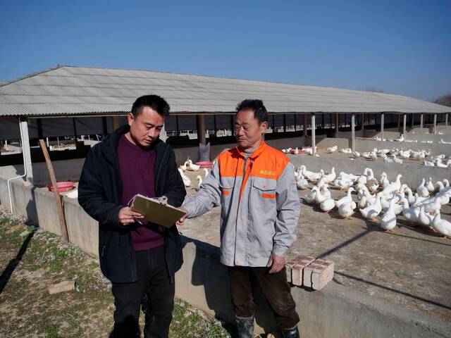 工作人员与谌寿生交流养殖技术。新华社记者郭杰文摄