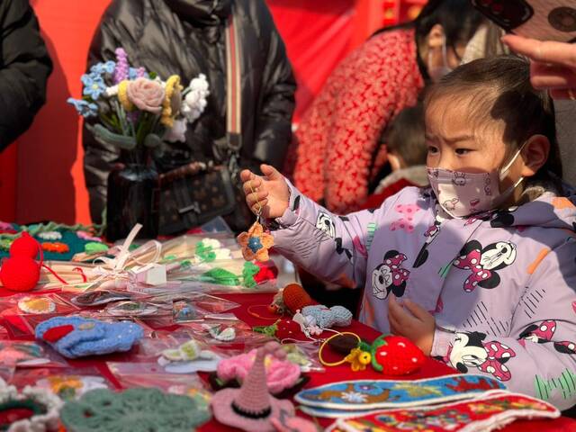 2月3日，徐州市贾汪区群众文化活动中心广场，小游客在观看传统饰品。殷萱桐摄