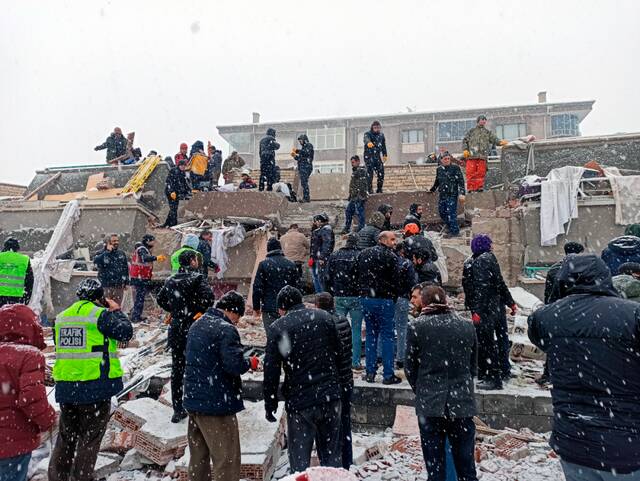 2月6日，人们聚集在土耳其马拉蒂亚一处倒塌的建筑附近。图源：新华社发，穆斯塔法·卡亚摄