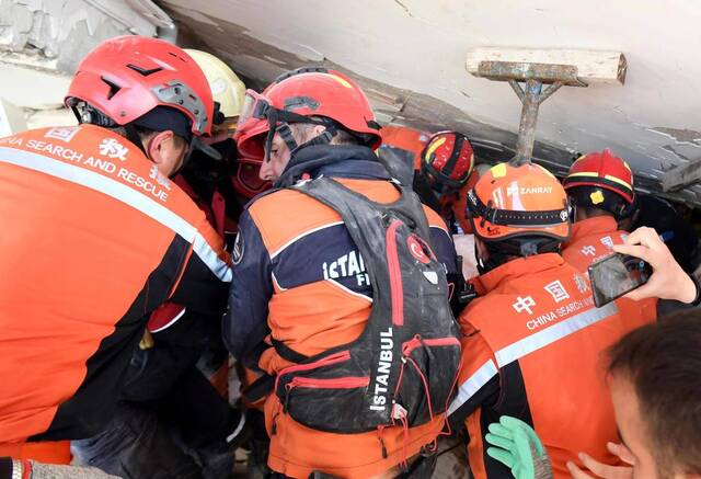 2月9日，在土耳其哈塔伊省安塔基亚市，中国救援队与土耳其救援队转移一名救出的女性幸存者。新华社记者沙达提摄