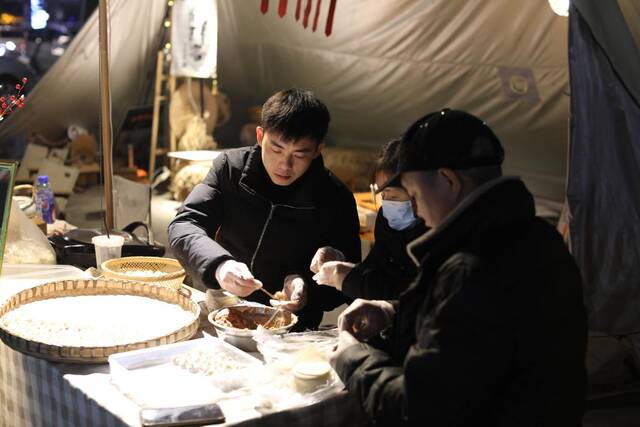 2月8日晚，李卫峰和家人在夜市摊位上包生煎包。新华社记者周思宇摄