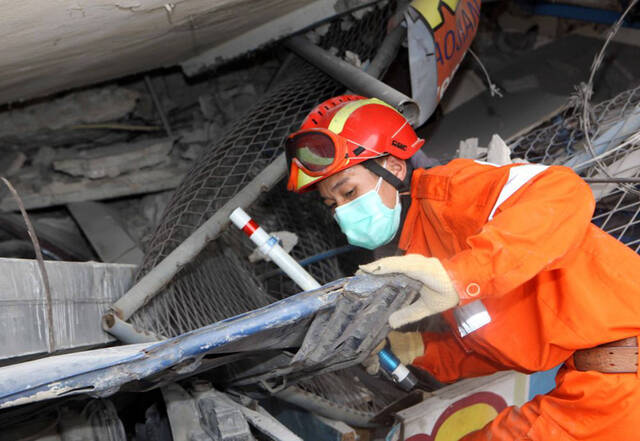 2010年1月19日，中国搜救队员在太子港市受灾最严重的地区废墟上搜寻生命迹象。新华社记者袁满摄