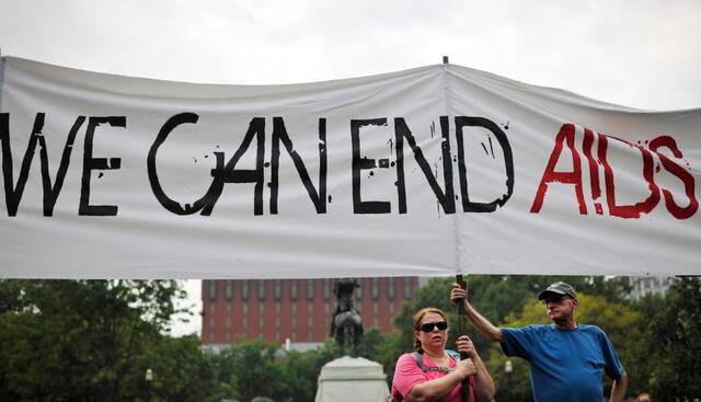 2012年7月24日，在美国首都华盛顿白宫外，人们举起“我们能结束艾滋病”的横幅。新华社记者张军摄