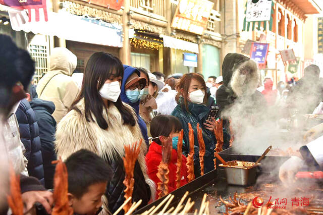 青海平安驿·河湟民俗文化体验地，游客们在小吃摊前排队。人民网陈晶摄