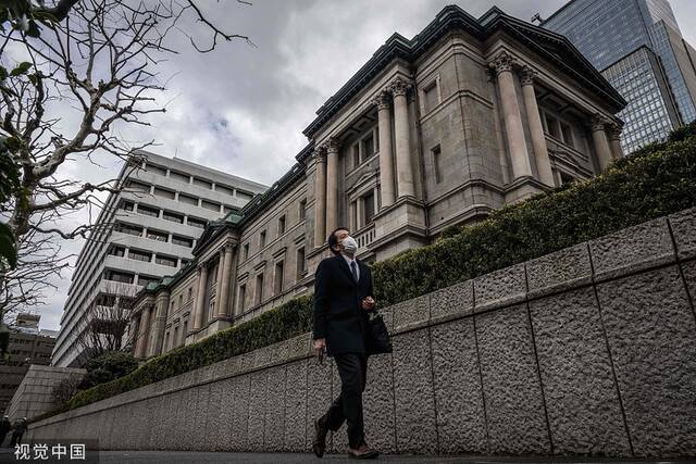 当地时间2023年2月14日，日本东京，一名行人经过东京的日本银行总部。人民视觉资料图