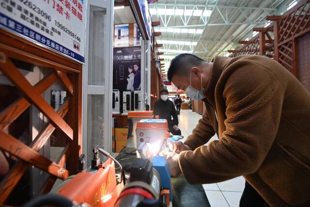 在中新天津生态城第三社区中心，一家开锁行经营者正在为顾客配钥匙。新华社记者赵子硕摄