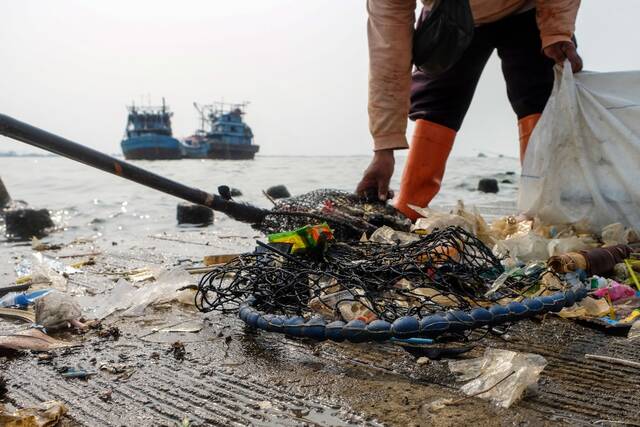 2021年6月8日，一名工作人员在印度尼西亚雅加达岸边清理垃圾。新华社发（维里摄）