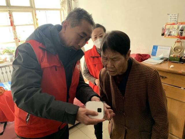 山西省太原市志愿者张建中给独居老人讲解一键呼叫器的使用方法。（新华社记者魏飚摄）