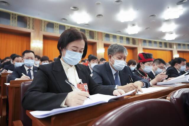 ▲3月5日，第十四届全国人民代表大会第一次会议在北京人民大会堂开幕。这是代表们在认真听会。图/新华社