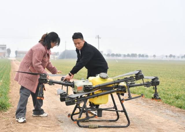 在陕西省宝鸡市陈仓区慕仪镇齐西村的农田，齐叶叶（左）与齐昆调试植保无人机（2023年2月27日摄）。新华社记者张博文摄