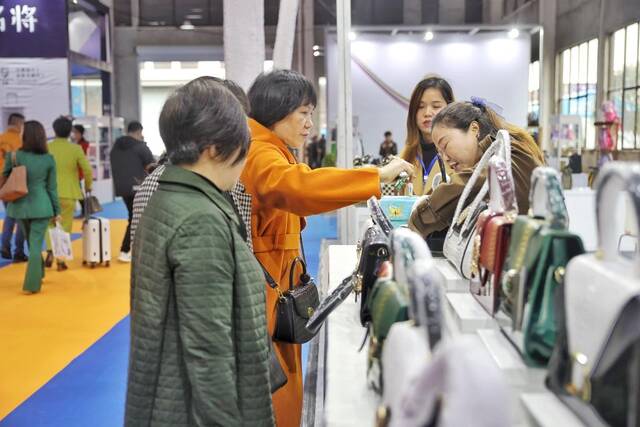 图为消费者在湖南省永州市蓝山县皮具箱包博览会展厅内购买箱包。（彭华摄）