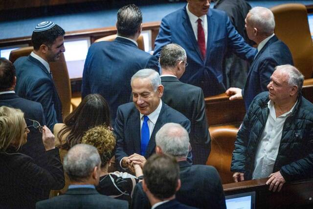 2022年12月29日，以色列新一届政府在议会宣誓就职。图为总理内塔尼亚胡（中）出席议会会议。新华社/基尼图片社