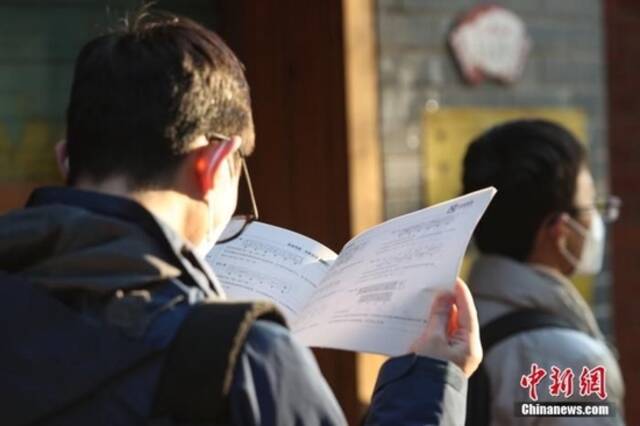 资料图：1月8日，江西南昌市第二十八中学考点外，一名考生拿着资料在复习。中新社记者刘力鑫摄