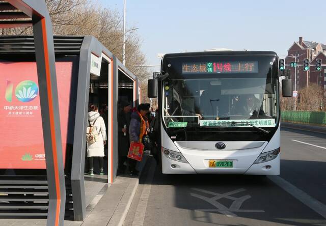 乘客在中新天津生态城的一座智慧公交站乘坐免费的纯电动公交车。