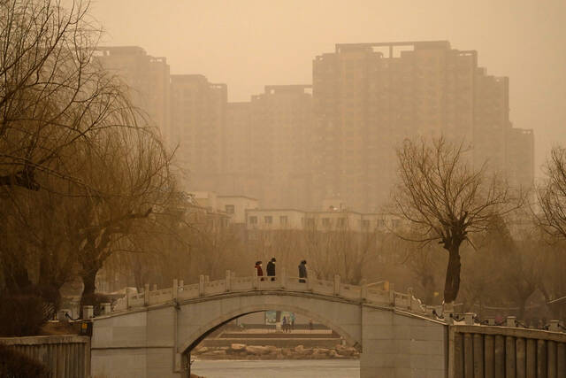 3月22日，吉林长春，市民在沙尘天气中出行。长春市气象台当日7时30分发布沙尘蓝色预警信号。中新社张瑶摄