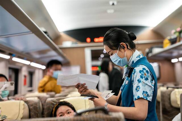 4月13日，首发列车乘务员在列车上查验车票。新华社记者胡超摄