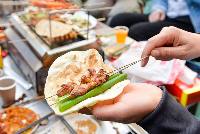 2023年3月31日，山东淄博，在一家烧烤店内，食客展示小饼、蘸料以及各种烤串包容一切的吃法。视觉中国图