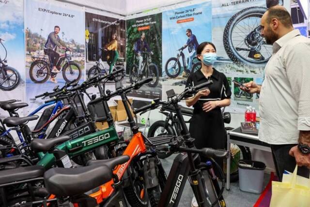 4月15日，采购商（右）在广交会新设置的新能源及智能网联汽车展区了解中国电动自行车产品。新华社记者刘大伟摄