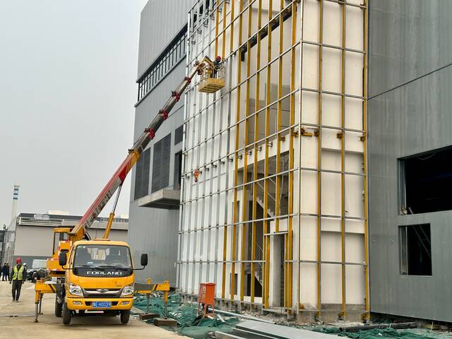 安彩高科药用玻璃项目建设现场，施工人员正在进行最后的外墙包装收尾工作。