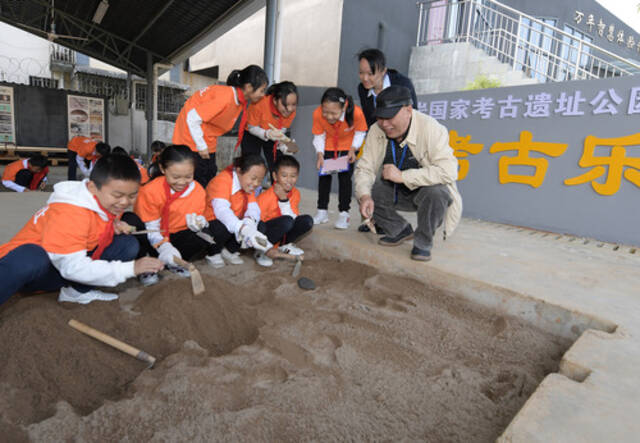 图为2019年，在位于桂林的甑皮岩国家考古遗址公园，考古专家（右一）指导孩子们模拟发掘。新华社记者李贺摄