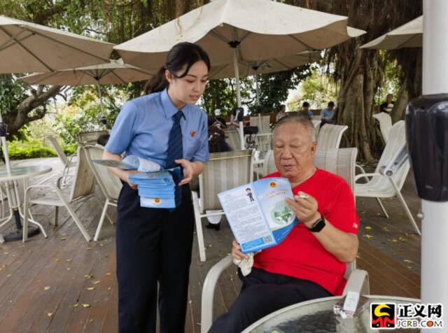 在鳄鱼山景区内的公益诉讼检察监督联系点,检察官助理向群众发放普法宣传手册。钟心宇摄