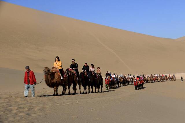 游客骑着骆驼在鸣沙山月牙泉景区游览（4月29日摄）。新华社发（张晓亮摄）