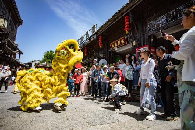 4月30日，游客在重庆市秀山土家族苗族自治县洪安镇老街观看舞狮表演。（胡程摄）