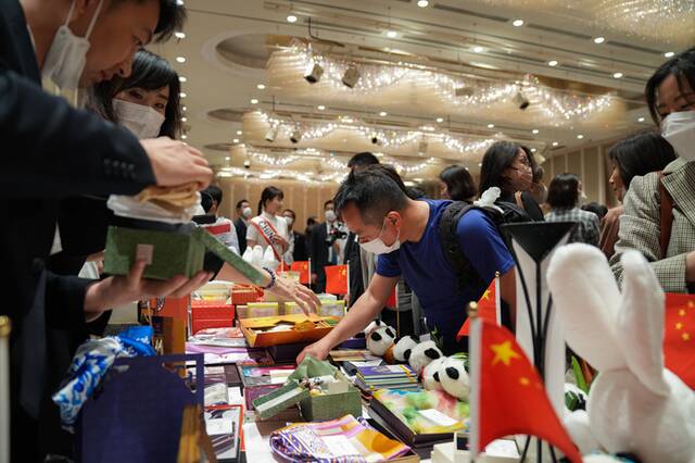 图为义卖活动参加者在中国摊位前挑选商品。（记者张笑宇摄）