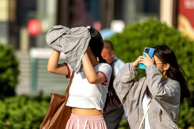 5月14日，郑州，街头市民轻装出行，用各种方式防晒避暑。