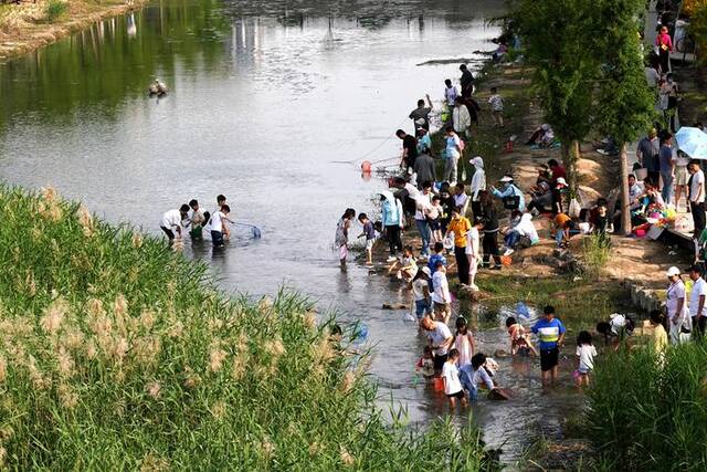 5月14日，郑州市郊东风渠河畔大批老少，冒着烈日前来河边避暑降温，共度周日闲暇时光。