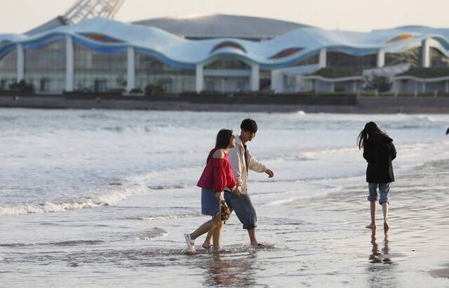 5月8日下午，青岛石老人海水浴场海边，游客穿夏装游玩。
