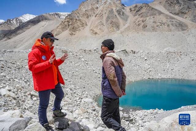 在珠峰海拔约5300米处，科考队员在探讨冰面湖的形成原因（5月14日摄）。新华社记者孙非摄