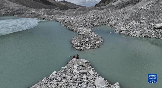在珠峰海拔约5300米处的冰前湖，科考队员在取水样（5月12日摄，无人机照片）。新华社记者晋美多吉摄