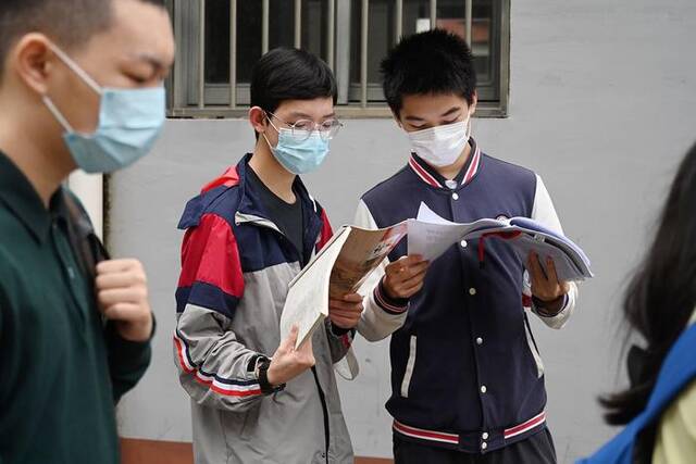 2023年6月7日，上海，华东理工大学附属中学考点，考生在排队进考场时看书复习。澎湃新闻记者朱伟辉图