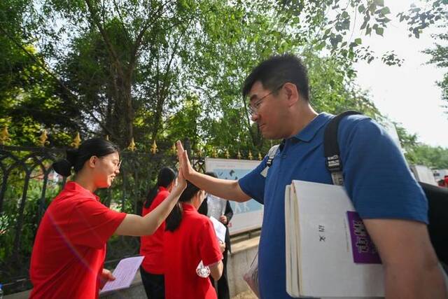 吉林省孤儿学校高专教育科主任赵春雨与考生击掌祝福。新华社记者颜麟蕴摄