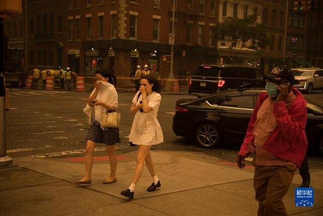 6月7日，行人以手掩住口鼻走在烟尘笼罩的美国纽约街头。新华社发（郭克摄）