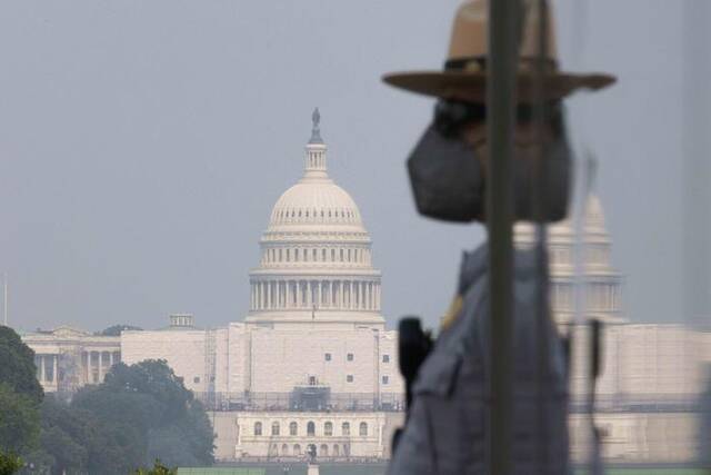 ▲当地时间2023年6月7日，在烟尘笼罩的美国首都华盛顿，国家公园的一名工作人员戴着口罩在户外工作。图/新华社
