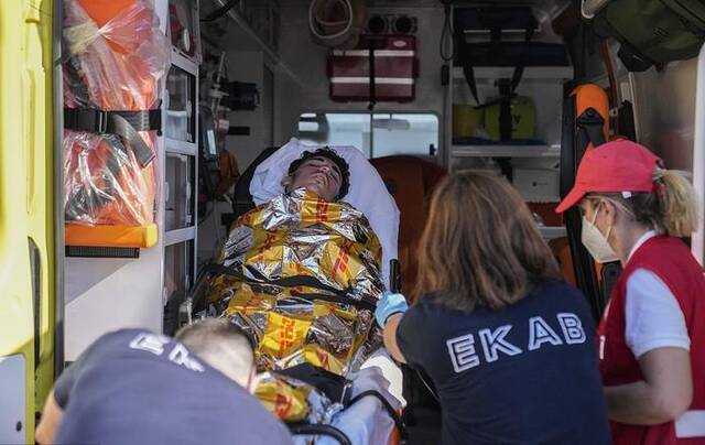 当地时间2023年6月14日，希腊卡拉马塔港，医护人员将一名海难中的幸存者抬到救护车上。
