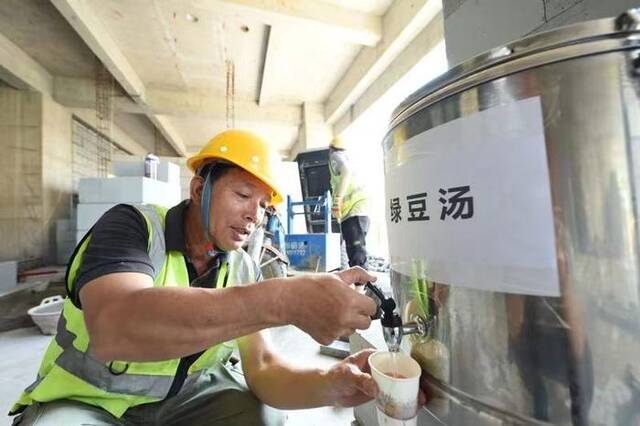 建筑工人在河北工程大学附属医院复兴院区项目施工现场饮用绿豆汤。新华社记者赵鸿宇摄