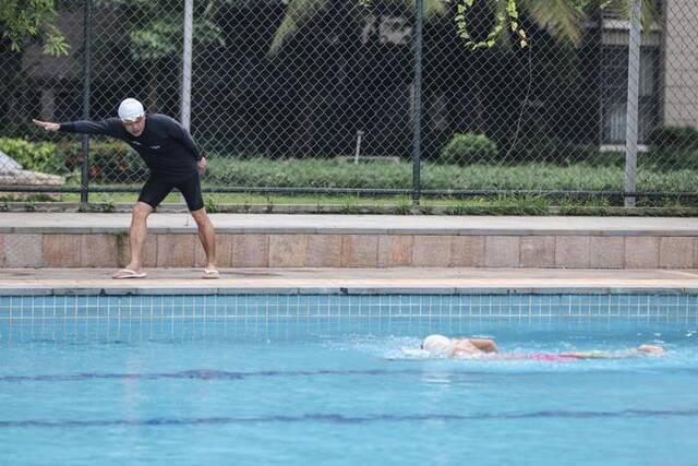 6月12日，陈勋虎在泳池边指导儿子训练。新华社记者张丽芸摄